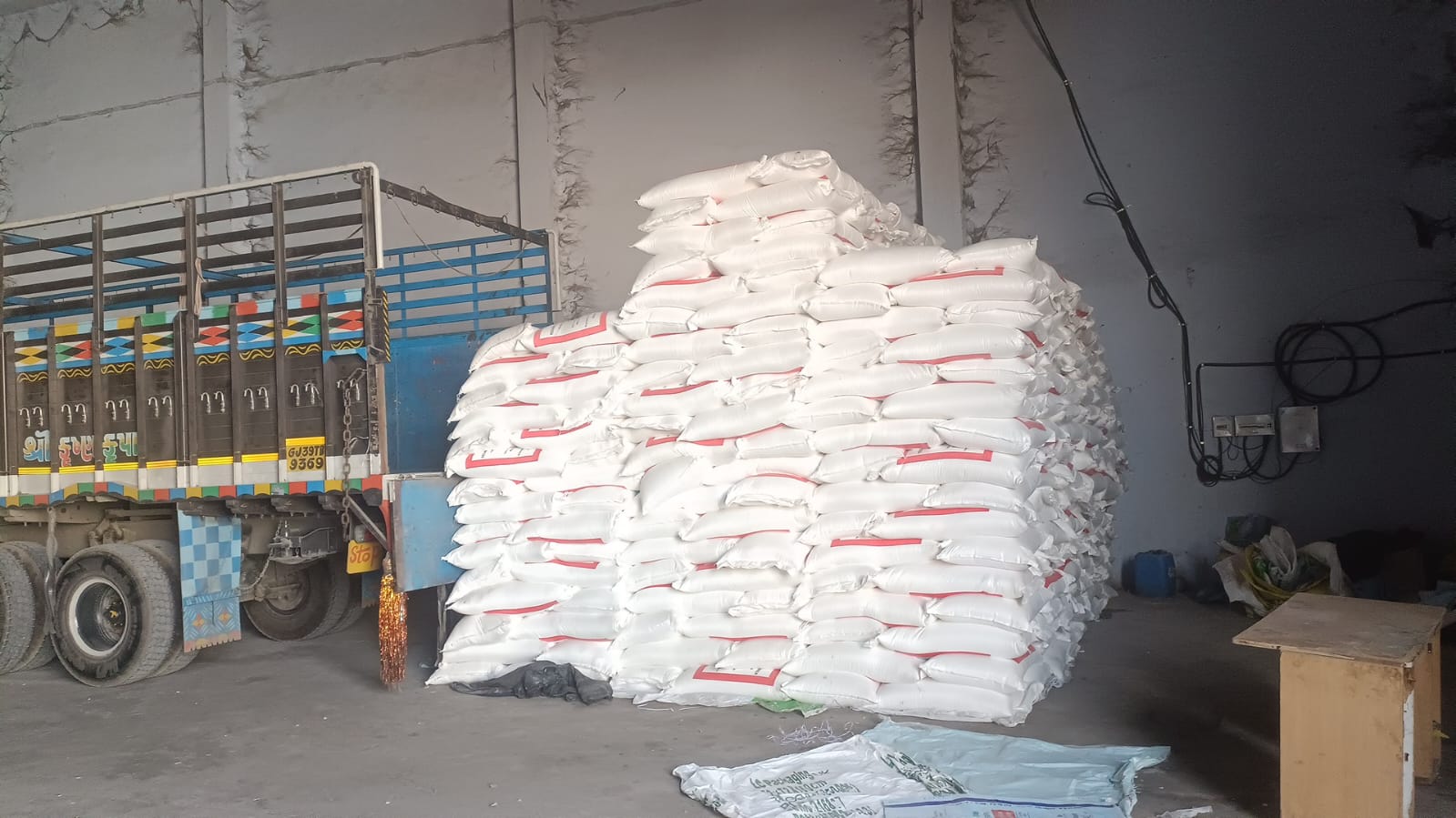 Stack of white poly bags with a red stripe next to a truck in a covered shed