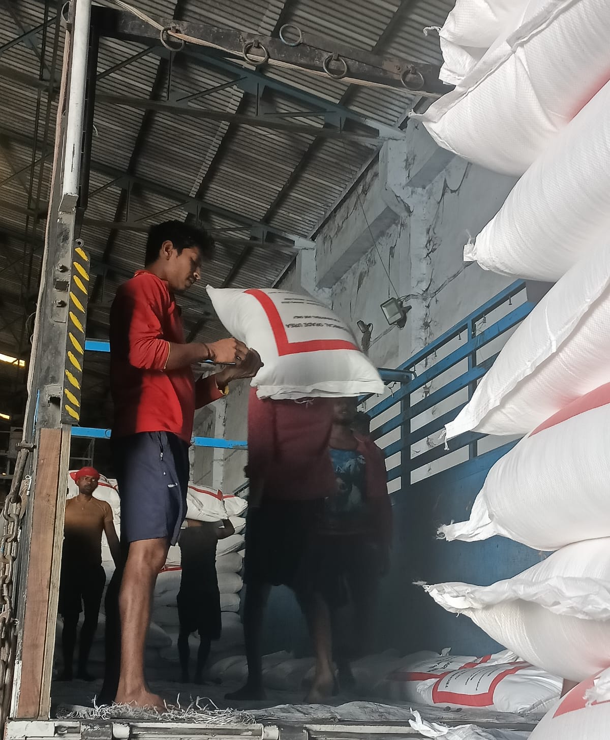 Workers carrying white poly bags into a truck
