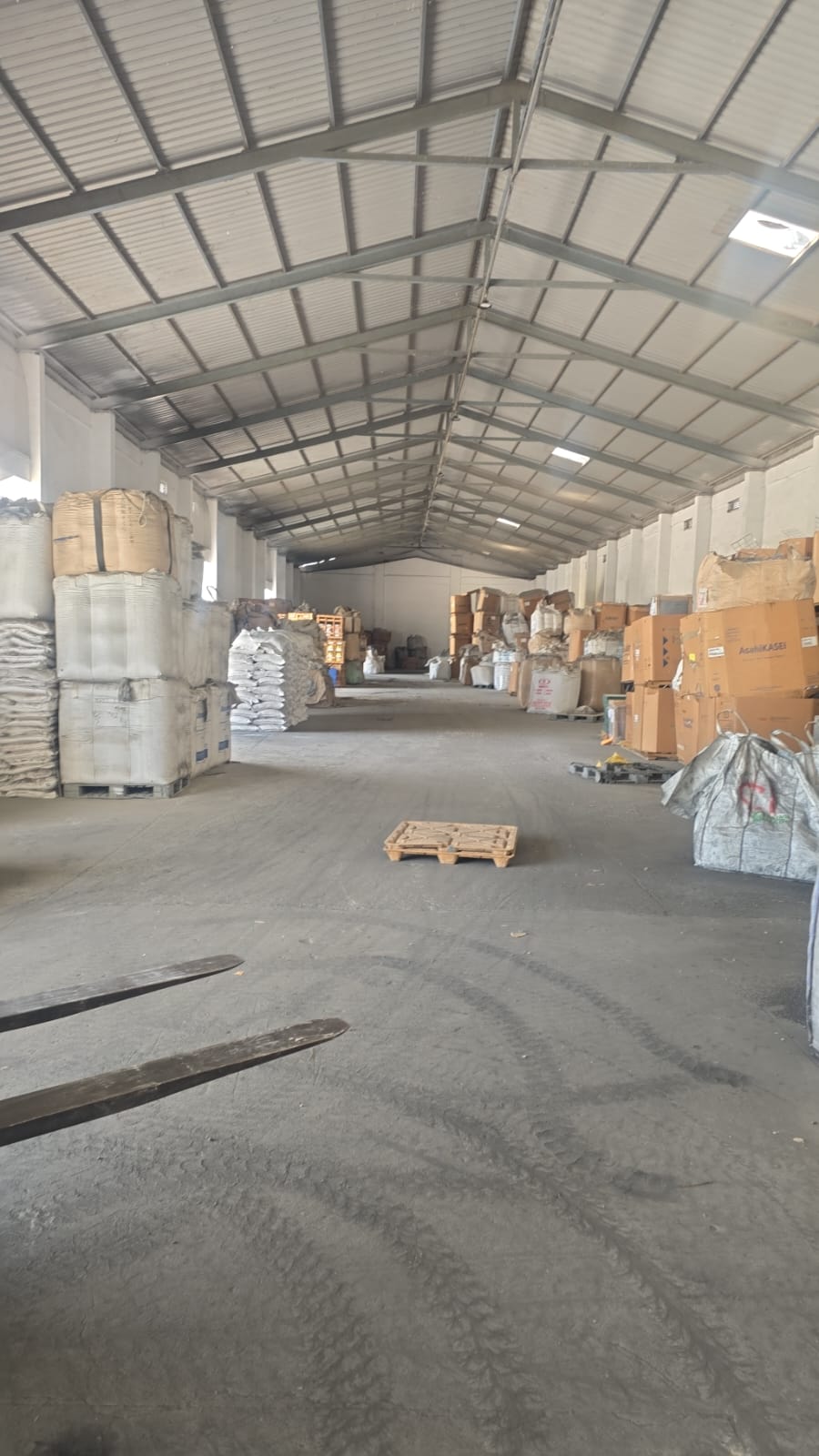 Long warehouse aisle with stacked bags, jumbo bags and cartons